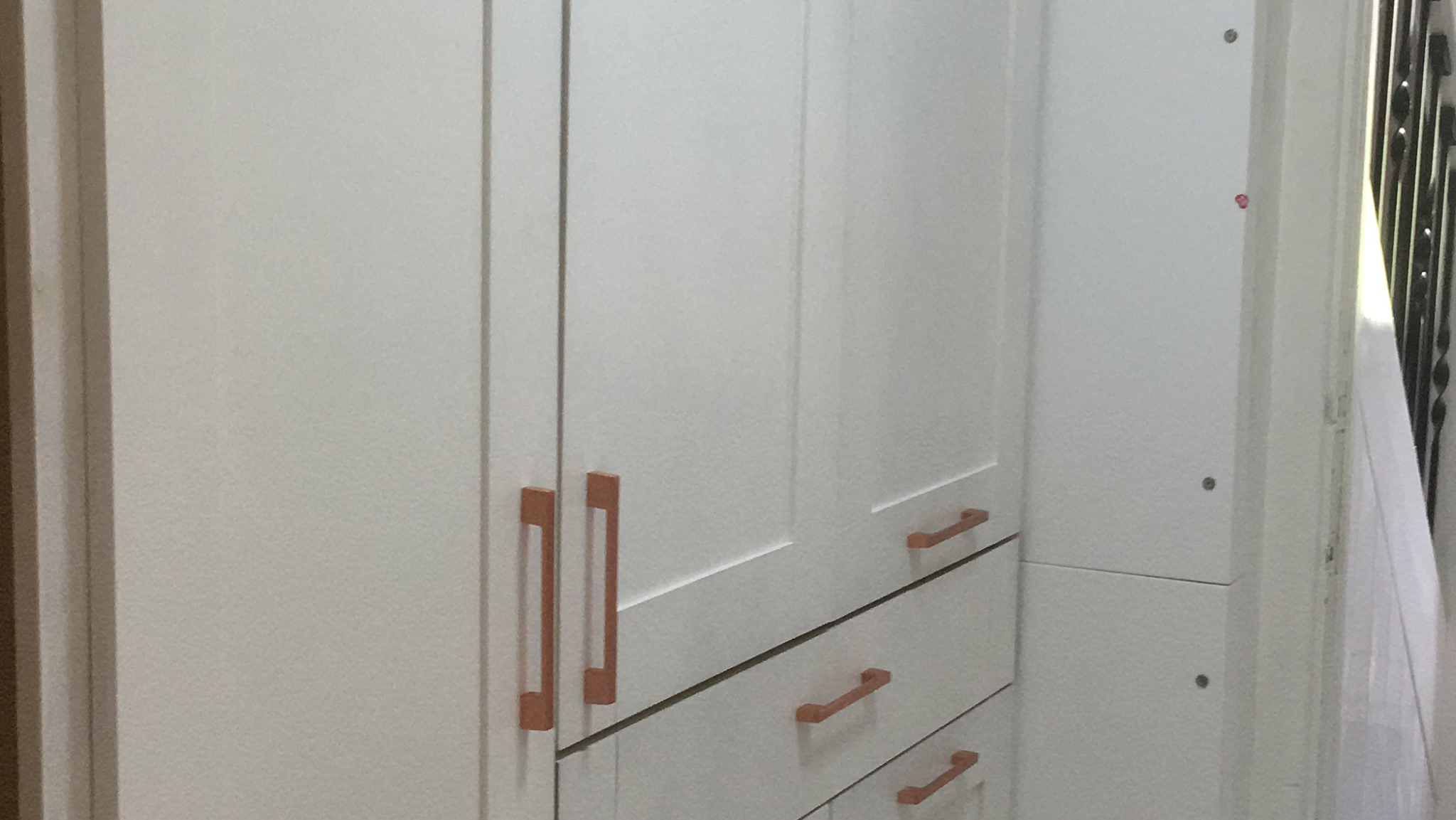 White fitted cupboards and drawers with copper bar handles