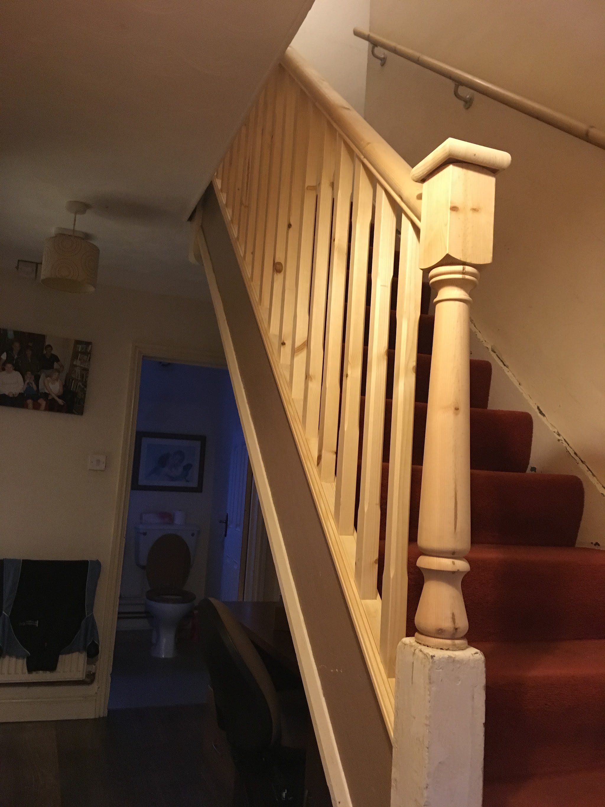A timber staircase balustrade with a turned newel post