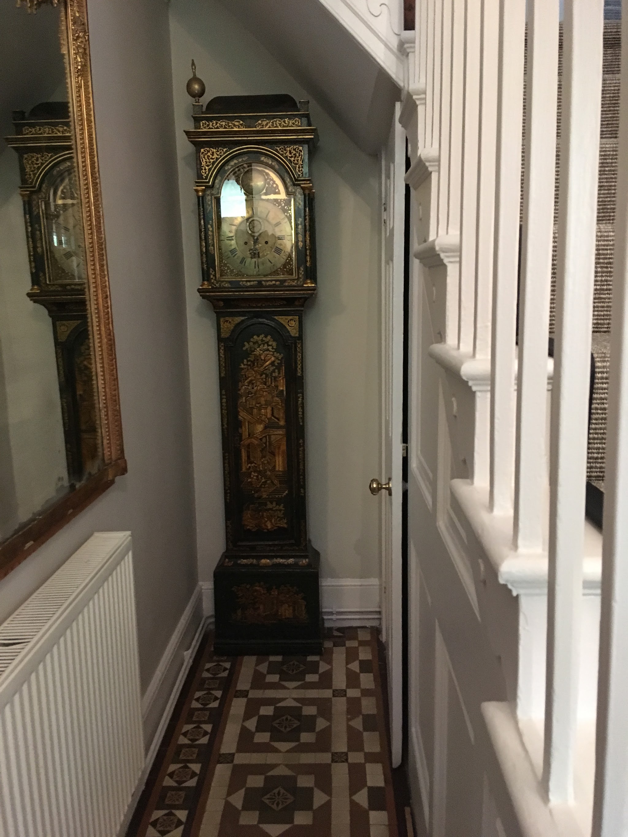 Hallway with a white painted balustrade and tiled floor